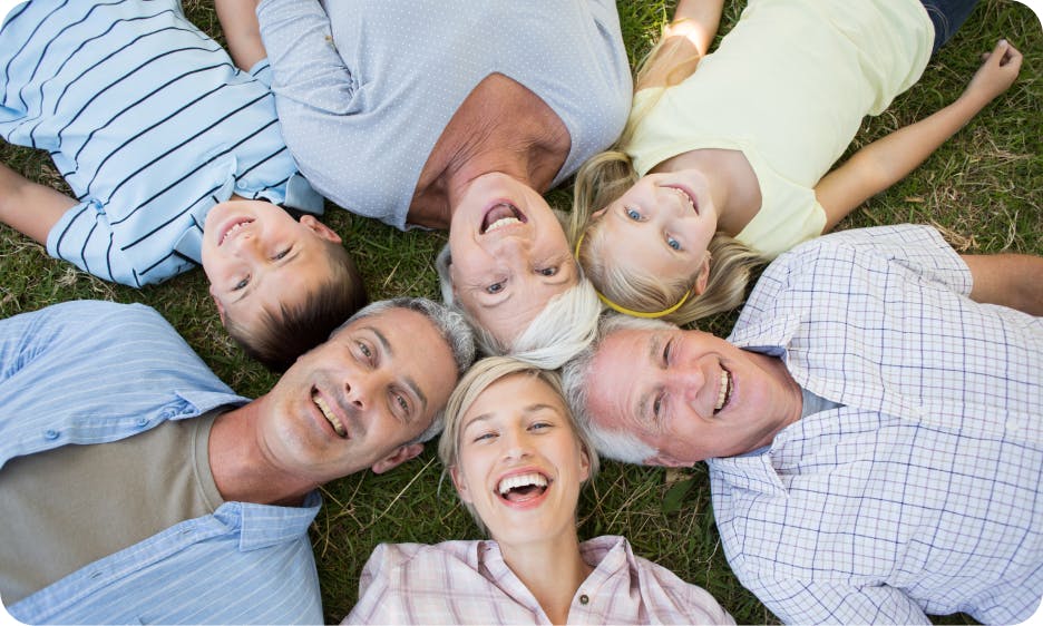 three people laying in a circle on the grass smiling at the camera